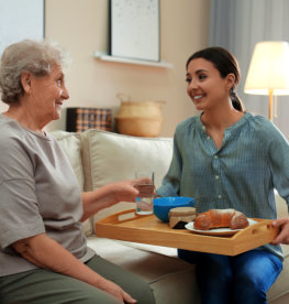 caregiver giving food to elderly woman