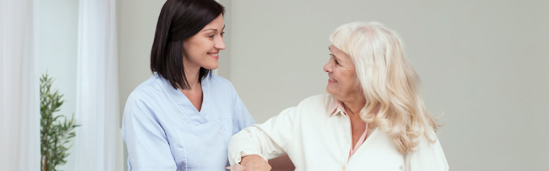 Cheerful caregiver helping elderly women