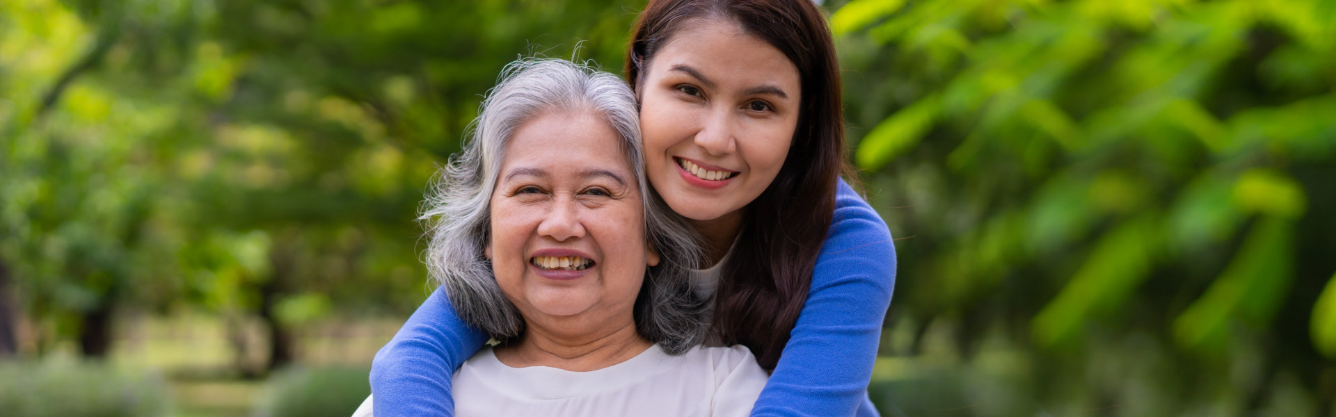 young caregiver hugging elderly woman