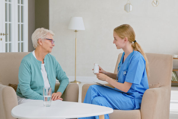 caregiver giving medicine to elderly woman